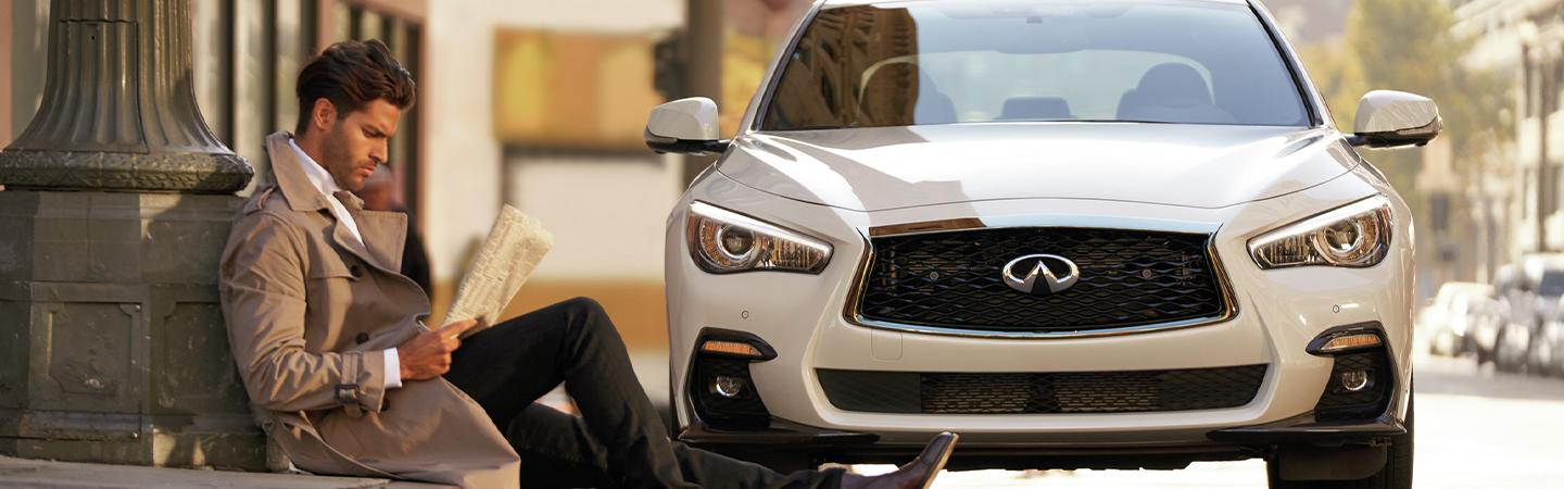 man sitting in front of the white color INFINITI q50