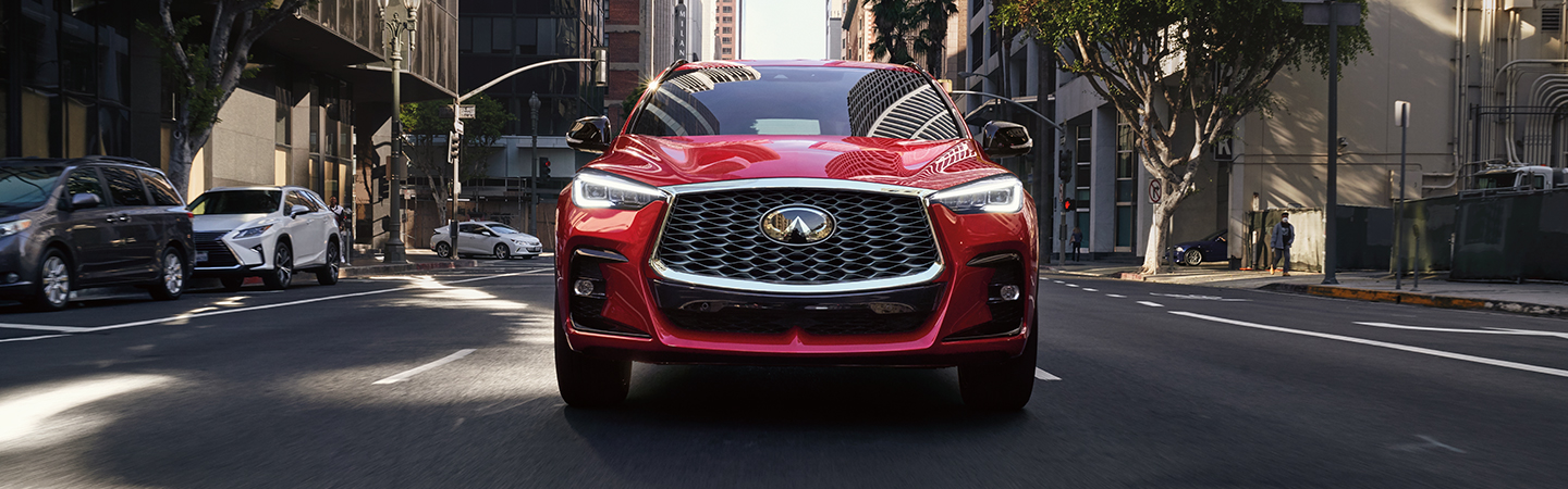 Front view of a red INFINITI QX55 driving through the city.