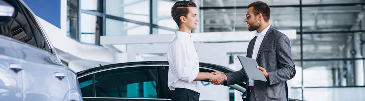 2 men shaking hands inside car showroom