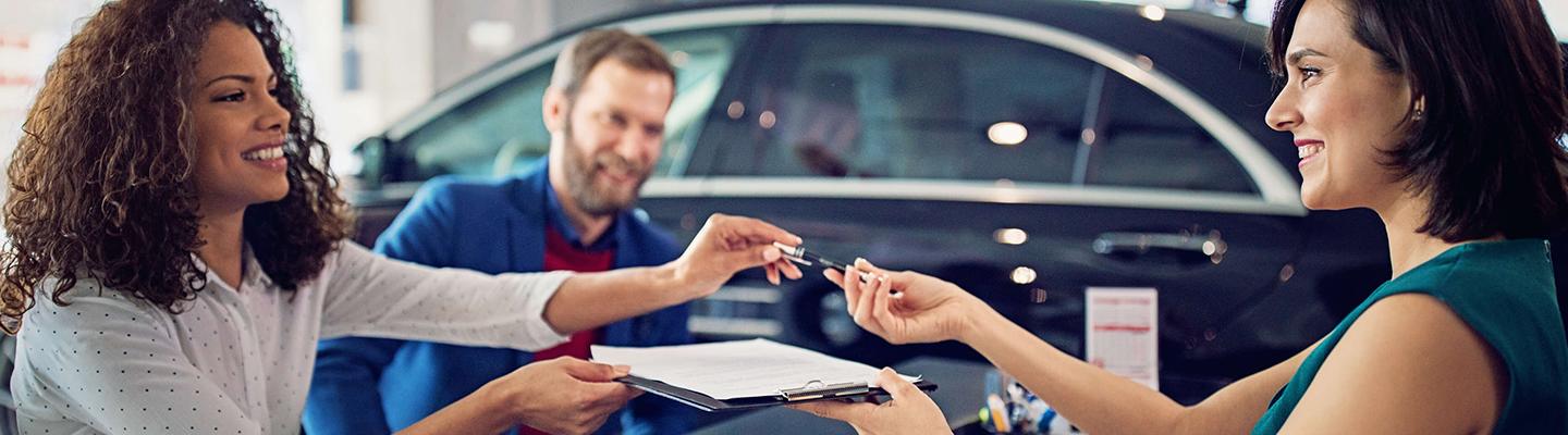 New VW customers signing their new VW's paperwork at the dealership