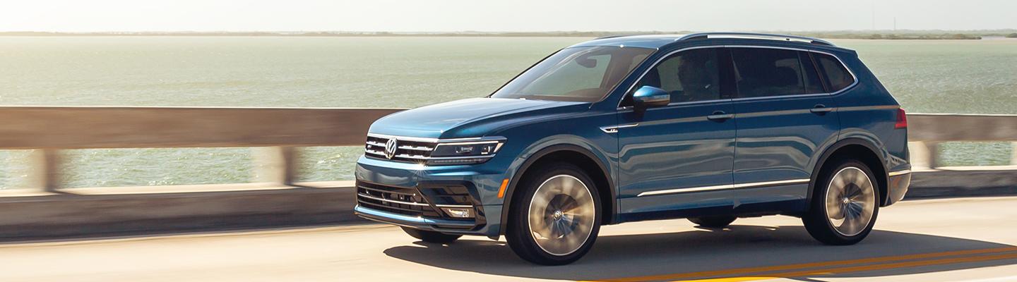 A blue 2021 Volkswagen Tiguan in motion through a bridge.